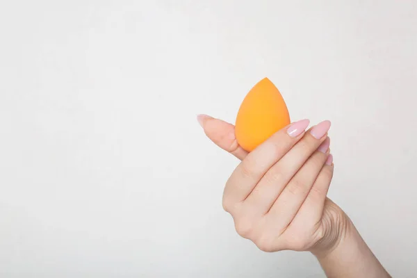 Крупный план женской руки, держащей оранжевую яичную губку над косточкой — стоковое фото