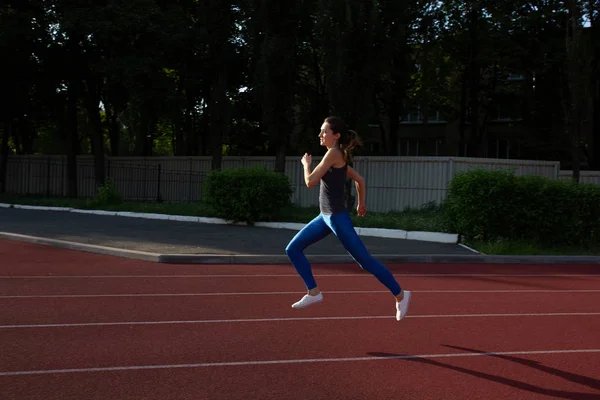 Chica atlética con ropa deportiva corriendo en el estadio vacío — Foto de Stock