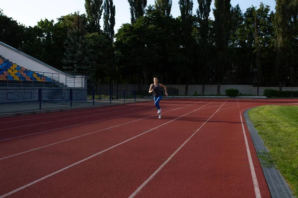 Mujer de fitness corriendo en el estadio vacío por la noche — Foto de Stock