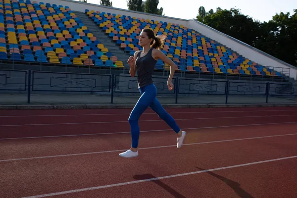 Mujer de fitness delgada corriendo en el estadio por la noche — Foto de Stock