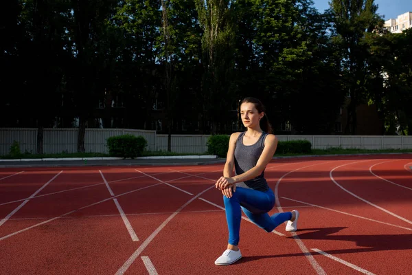 Atractiva chica deportiva estirándose antes de correr en el estadio . — Foto de Stock