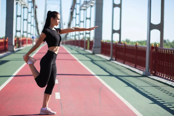 Mujer fuerte fitness estirándose en el puente peatonal antes — Foto de Stock