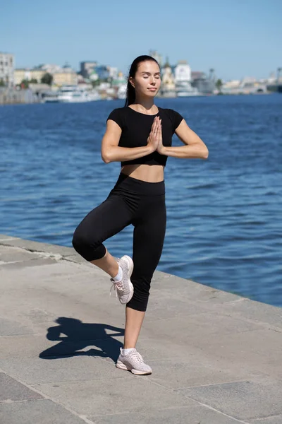 Kaukaska opalona brunetka kobieta uprawia jogę w rzece — Zdjęcie stockowe