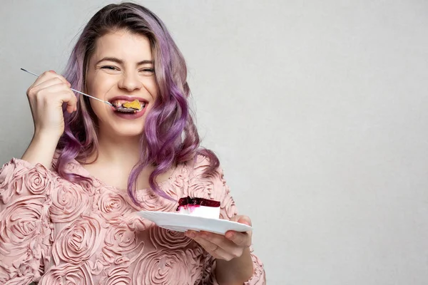 Vrolijk meisje met paars haar eten zoete kaastaart over GRE — Stockfoto