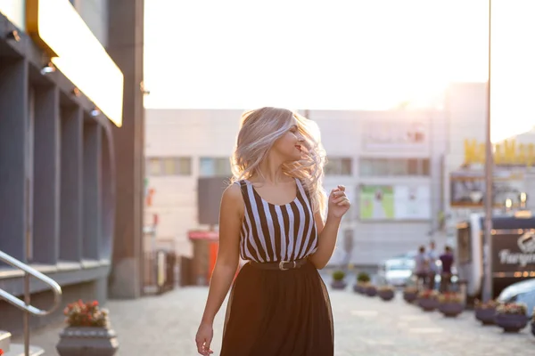 Счастливая блондинка с развевающимися волосами, позирующая с вечерним светом — стоковое фото