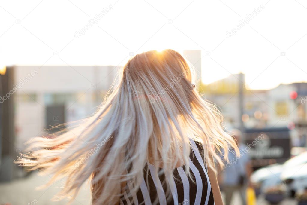 Gorgeous blonde woman with fluttering hair posing with evening l