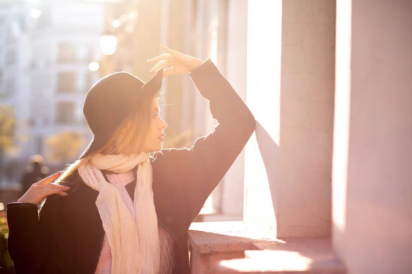 Stylish blonde lady wearing coat and hat posing at the old stree — Stock Photo, Image