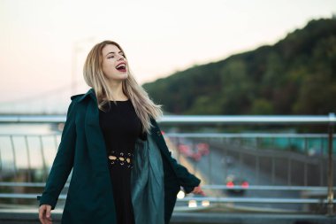 Yeşil ceket giyen duygusal genç kadın köprü wi poz