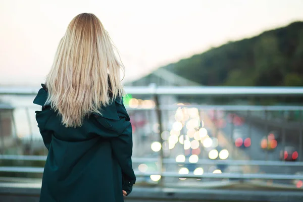 Pretty young woman with long hair posing at the bridge. Back vie — Stock Photo, Image