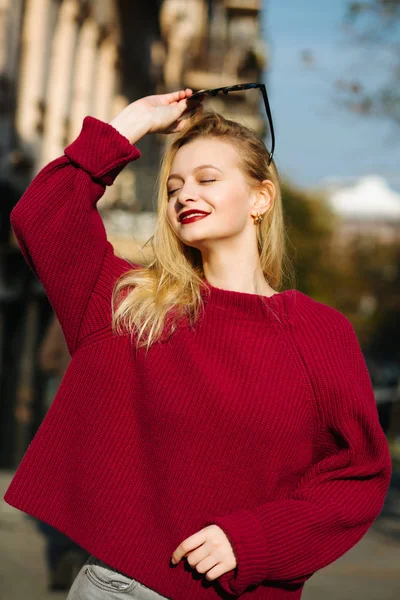 Cheerful blonde woman with red lips wearing oversize knitted swe — Stock Photo, Image