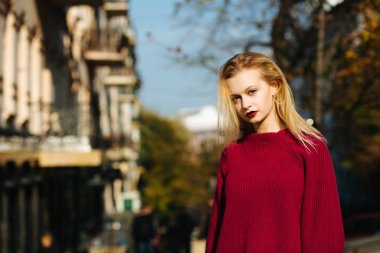 Güneş ışığıyla poz veren kazak giyen muhteşem bayan. Boş aralık