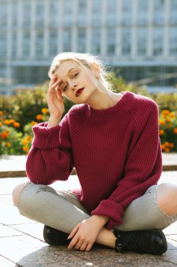 Awesome genç model örme kazak ve yırtık kot sitti giyiyor