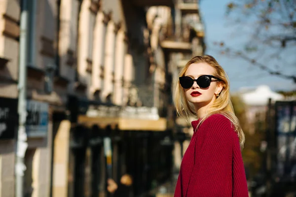 Gorgeous woman wearing sweater and sunglasses posing at the city — Stock Photo, Image