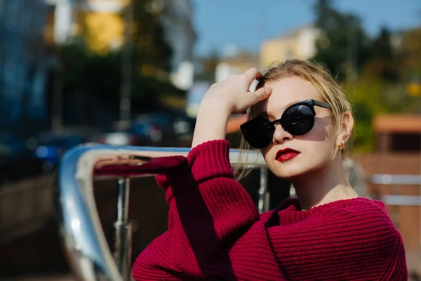 Glamorous blonde woman wearing sweater and glasses posing at the — Stock Photo, Image