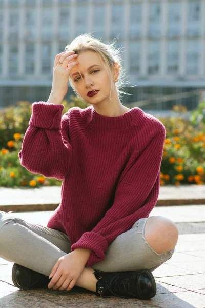 Fabulous young model wearing knitted sweater and torn jeans sitt — Stock Photo, Image