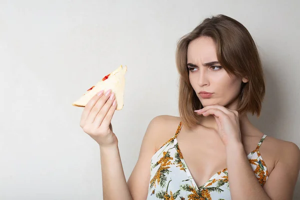 Vermoeden brunette meisje student het eten van een sandwich over een grijs b — Stockfoto