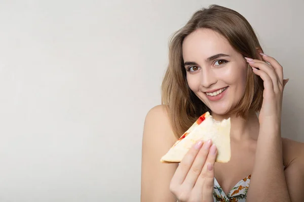 Vrolijke brunette meisje student het eten van een sandwich over een grijs BAC — Stockfoto