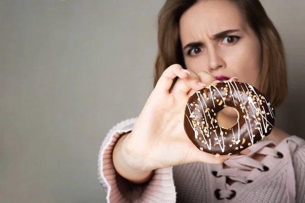 Bang brunette meisje met natuurlijke make-up houden donut tegen een — Stockfoto