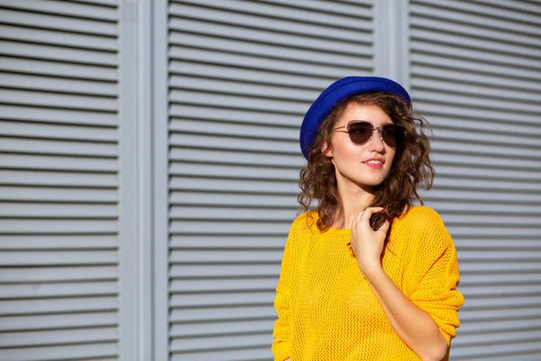 Ulica portret pięknej dziewczyny ubrany w niebieski kapelusz i żółty Knitt — Zdjęcie stockowe