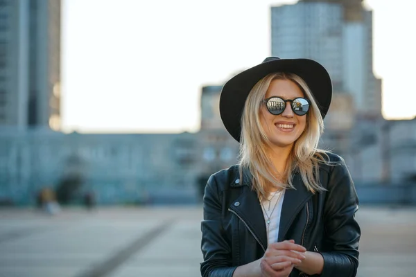 Outdoor fashion portrait of a positive blonde woman wearing hat — Stock Photo, Image