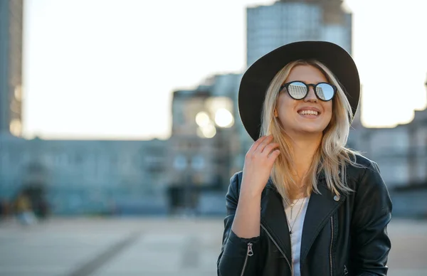 Outdoor fashion portrait of a merry blonde woman wearing hat and — Stock Photo, Image