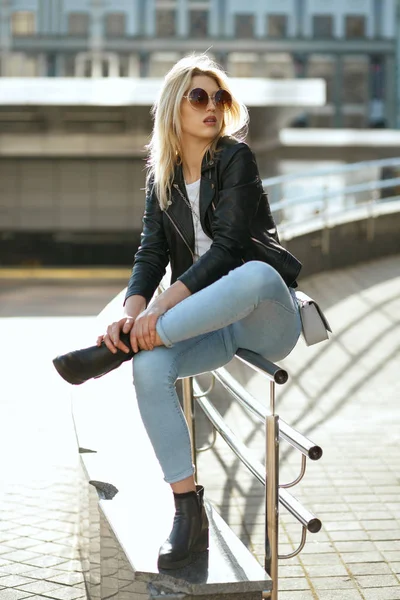 Atrakcyjna młoda kobieta ubrana w dżinsy i kurtka siedząca na Stree — Zdjęcie stockowe