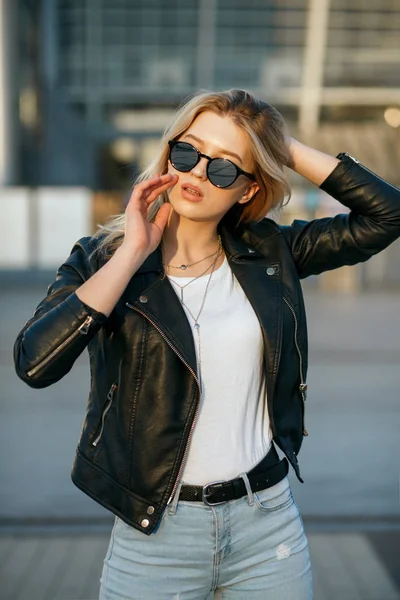 Street shot of young stylish girl wearing sunglasses and black j — Stock Photo, Image