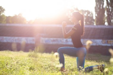 İnce fitness kız güneş parlama ile stadyumda lunges yapıyor.