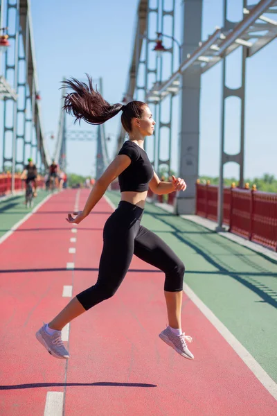 Preciosa atlética mujer de pelo largo saltando en la pista de jogging —  Fotos de Stock