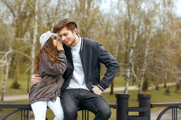 Little sister telling secrets to her brother at the park. Empty