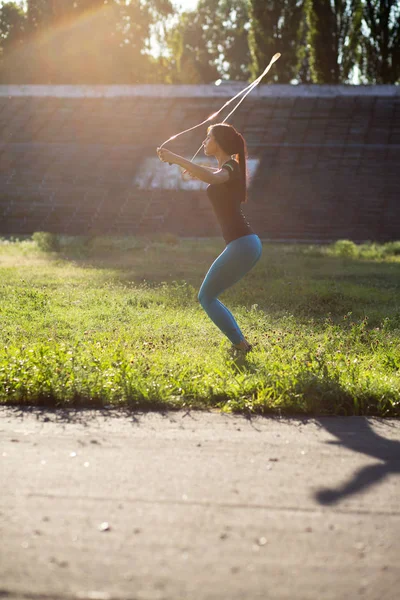 Atractiva chica deportiva haciendo ejercicio con cuerda de salto en los rayos del sol — Foto de Stock