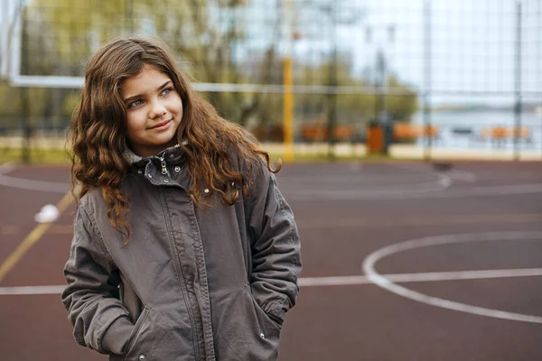 Menina alegre com cabelo encaracolado em pé em um playgroun de rua — Fotografia de Stock