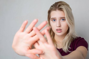 Endişeli sarışın kız gri duvar üzerinde stop jest gösteren. Alanı
