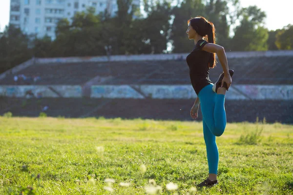 Prachtvolle Fitness-Frau dehnt sich vor dem Training im Stadion. — Stockfoto