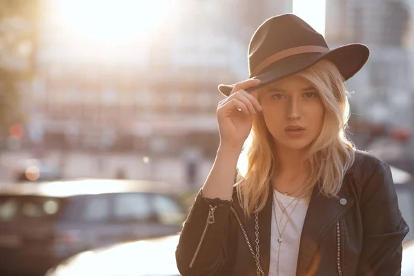 Modieuze blonde vrouw met zwarte hoed poseren met warme zon — Stockfoto