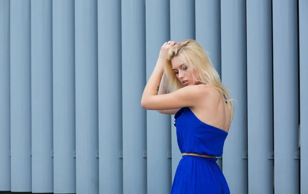 Гламурная блондинка в синем платье, позирующая возле металлического затвора — стоковое фото