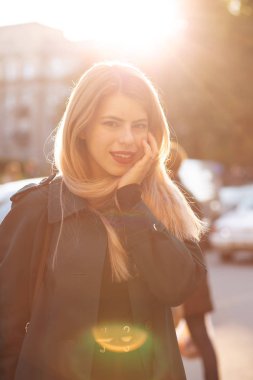 Şık bir ceket giyen sevimli genç kadın yolda poz 