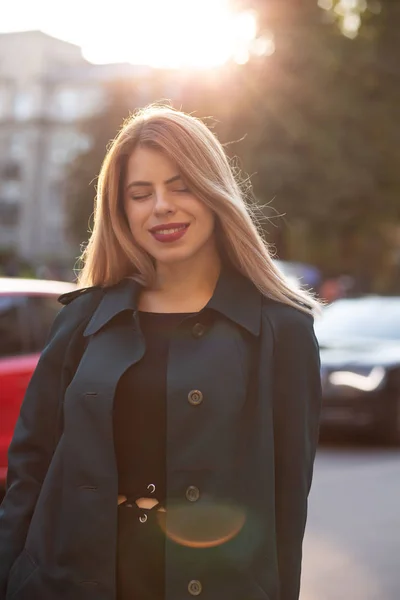 Cheerful young model wearing stylish coat posing at the road in — Stock Photo, Image