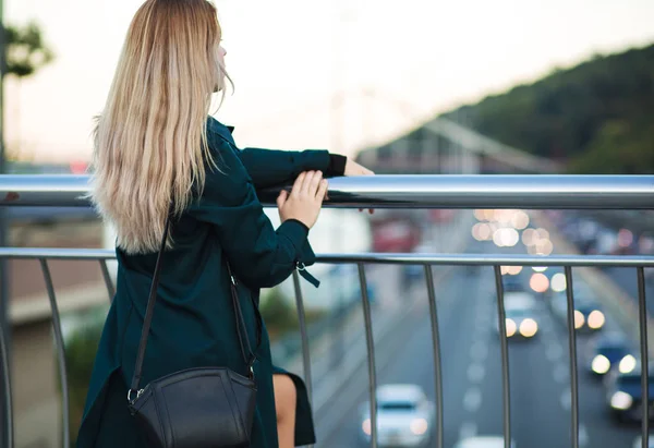 Pretty young woman wearing green coat and holding purse posing a — Stock Photo, Image