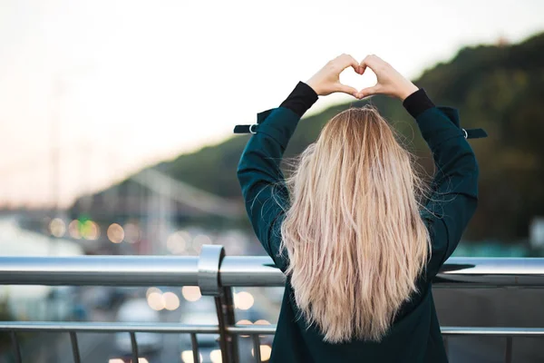 Lifestyle shot: charming happy woman showing heart sign near the — Stock Photo, Image