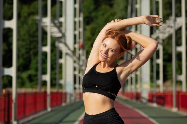 Neşeli atletik kadın köprüde ellerini germe yapıyor 