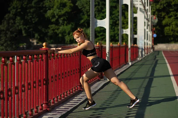 Lovely athletic woman doing stretching workout at the bridge in — Stock Photo, Image