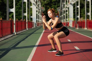 Atletik kırmızı saçlı kız elastik re ile mekit-up yapıyor çömelme