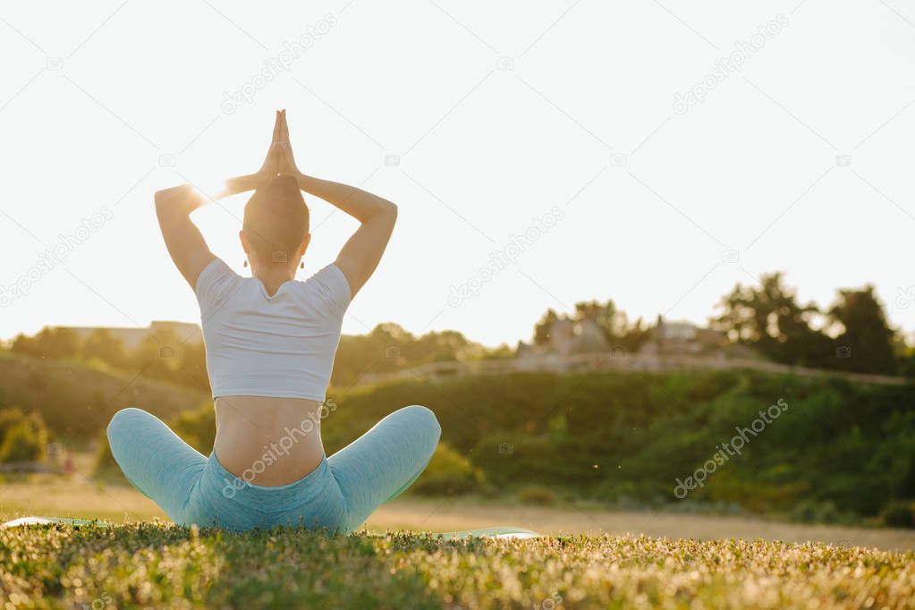 Splendid brunette girl relaxing in nature and practicing yoga in