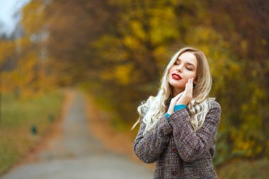 Parkta poz veren palto giyen şehvetli kadın