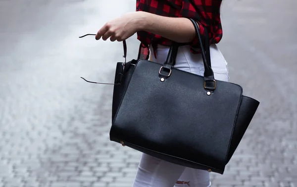 Kobieta trzyma czarną skórzaną torebkę — Zdjęcie stockowe