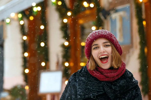 Positive girl with red lips walking during snowfall — Stock Photo, Image