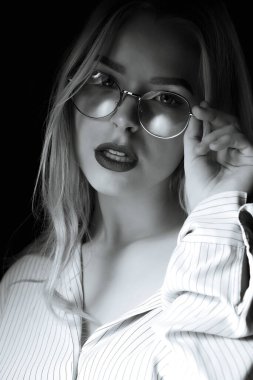 Zarif bir kadının dramatik portresi gölgede poz veren gözlükler takıyor. Siyah ve beyaz renk