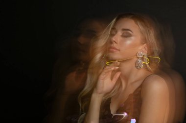 Mükemmel makyajlı şık genç bir kadın bulanık ışıkla poz veriyor. Metin için boşluk