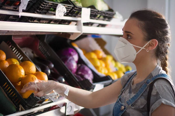 Woman who goes out to buy at a supermarket and is choosing fruit and vegetables. Woman going out to buy with sanitary mask. Covid-19. Coronavirus